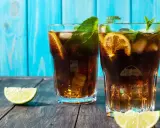 Dwa orzeźwiające drinki z rumem ciemnym, lodem, cytryną i miętą na drewnianym blacie.