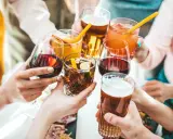 Ręce wznoszą kieliszki z winem, drinkami i piwem, celebrując wspólne chwile.