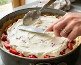 Nakładanie kremu z mascarpone na spód z truskawkami w tortownicy.