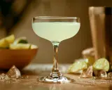 Orzeźwiający daiquiri w kieliszku, obok limonki i lodu. Idealny na upalne dni.
