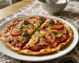 Pyszna pizza na tortilli z pomidorami, cebulą, szynką i serem, ozdobiona bazylią. Idealna na szybki obiad.