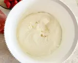 Gładki, puszysty krem z mascarpone w białej misie, gotowy do deseru. Obok miski widać miseczkę z truskawkami.