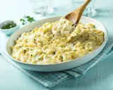 Pyszne mac and cheese przepis w białej misce, z drewnianą łyżką nabierającą porcję kremowego makaronu z serem.