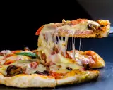 Rozciągający się ser z kawałka pysznej pizzy z kurczakiem, pomidorami i grzybami.