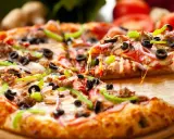 Gotowy spód do pizzy, z ciągnącym się serem, oliwkami, papryką i mięsem, aż chce się go włożyć do pieca!