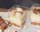 Pyszne ciasto Kinder Bueno w pucharkach, przełożone kremem i czekoladą, posypane orzechami.