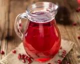 Szklany dzbanek z sokiem z granatu, otoczony owocami. Idealny do drinków, deserów, a także jako baza do sosów. Sok z granatu z czym łączyć?