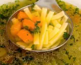 Łyżka nabiera aromatyczny bulion warzywny z marchewką i makaronem nitki.