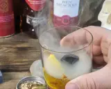 Szklanka z drinkiem otoczona dymem, obok butelki whisky i czaszka. Wyjątkowe drinki z dymem.