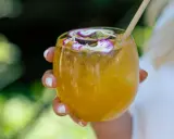Orzeźwiający drink z marakują, ozdobiony kwiatami i plasterkiem owocu. Idealny na upalne dni.