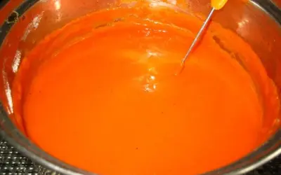 Gęsty, pomarańczowy sos pomidorowy do gołąbków w garnku, z metalową sondą termometru zanurzoną w środku.