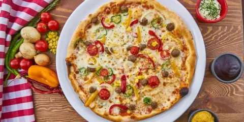 Pizza z mięsem mielonym, papryką, cebulą i kukurydzą. Obok sosy i warzywa, co zamiast śmietany?