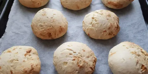 Świeżo upieczone bułki bez drożdży, lekko zarumienione, ułożone na papierze do pieczenia.