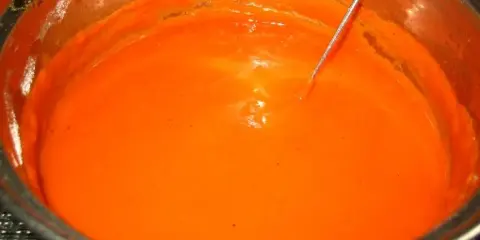 Gęsty, pomarańczowy sos pomidorowy do gołąbków w garnku, z metalową sondą termometru zanurzoną w środku.