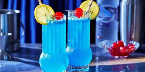 Dwa orzeźwiające drinki Blue Lagoon z cytryną i wiśnią, gotowe do podania.