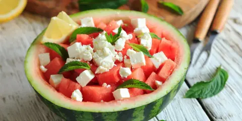 Orzeźwiająca sałatka z arbuzem, serem feta i miętą, podana w połówce arbuza. Idealna na letnie dni.