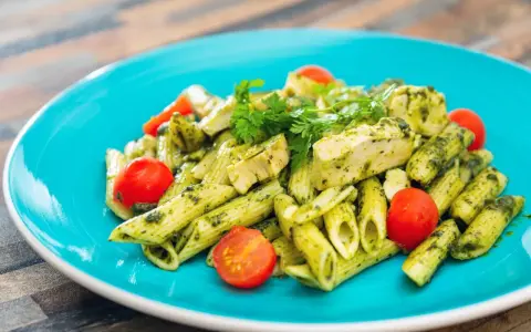 Penne z kurczakiem i pomidorkami koktajlowymi w sosie pesto, z dodatkiem mozzarelli.