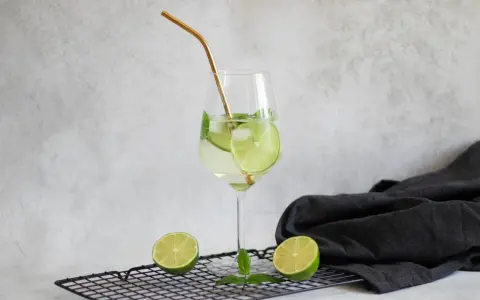 Orzeźwiający drink Hugo z limonką i miętą, idealne proporcje na lato. Złota słomka dodaje elegancji.