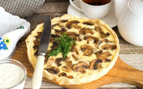Pyszna tarta z pieczarkami, podana z kubkiem herbaty i śmietaną. Idealna na jesienny obiad.
