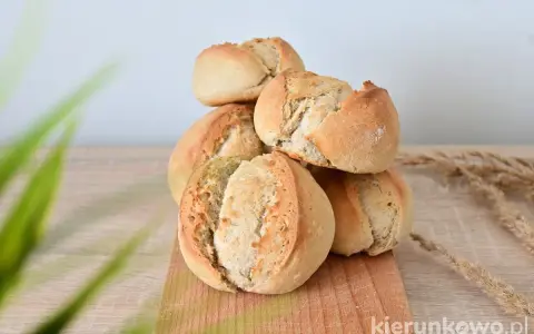 Stos świeżo upieczonych bułek na zakwasie, z chrupiącą skórką i puszystym wnętrzem, ułożonych na drewnianej desce.