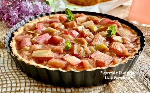 Pyszna tarta z rabarbarem, udekorowana listkami mięty, kusi swoim wyglądem.