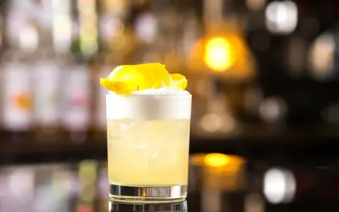 Klasyczny whisky sour z pianką i skórką cytryny, idealny na wieczór.