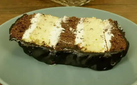 Kawałek ciasta z czekoladą i kremem budyniowym z mascarpone, polany błyszczącą polewą.
