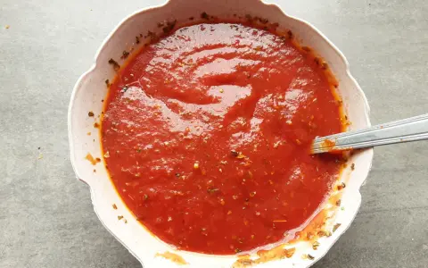 Domowy sos do pizzy, gęsty i aromatyczny, z ziołami w misce. Idealny na każdą okazję.