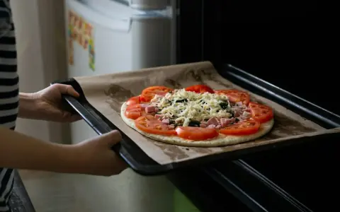 Wkładanie pizzy do piekarnika. Dzięki termoobiegowi ciasto będzie chrupiące, a ser idealnie roztopiony.