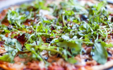 Pyszna pizza z tuńczykiem, rukolą i oliwkami, polana sosem balsamicznym. Idealna na szybki obiad.