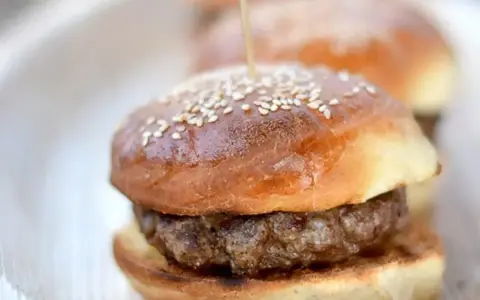 Mini burgery na talerzu, z sezamem na wierzchu. Idealne bułki do burgerów na przyjęcie.