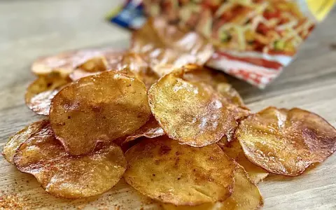 Chrupiące chipsy z piekarnika, lekko przypieczone, z widocznym opakowaniem w tle. Idealna przekąska!