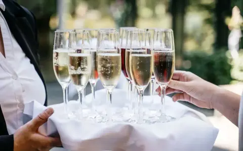 Taca z kieliszkami musującego wina, idealna do drinków typu Hugo. Zastanawiasz się, jakie prosecco do Hugo wybrać?