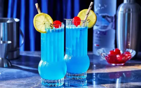 Dwa orzeźwiające drinki Blue Lagoon z cytryną i wiśnią, gotowe do podania.