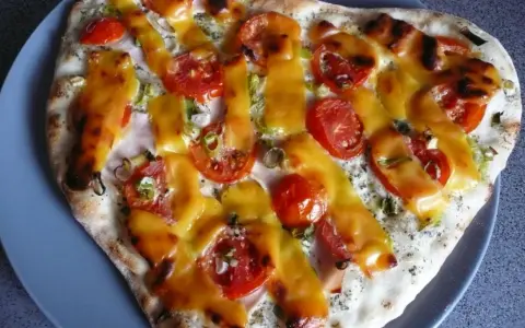 Pizza z pomidorami i serem, polana sosem śmietanowym.