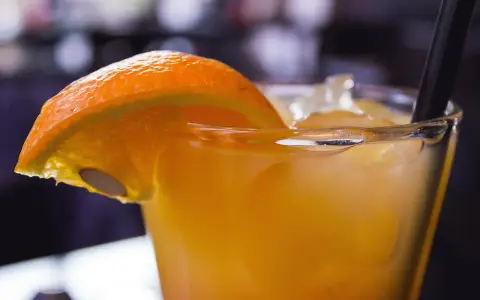 Orzeźwiający drink z suchym lodem, ozdobiony plasterkiem pomarańczy. Dymiący napój wygląda magicznie.