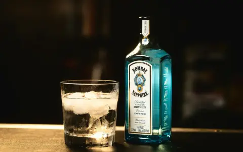 Szklanka z lodem i butelka Bombay Sapphire gin. Idealny składnik na orzeźwiający bombay sapphire drink.