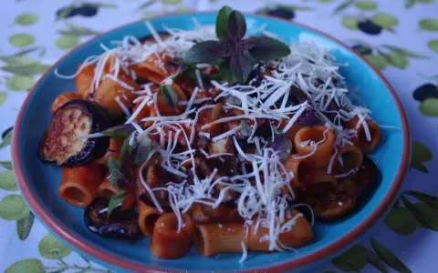 Rigatoni alla norma z bakłażanem, pomidorami i bazylią, posypane startym serem.