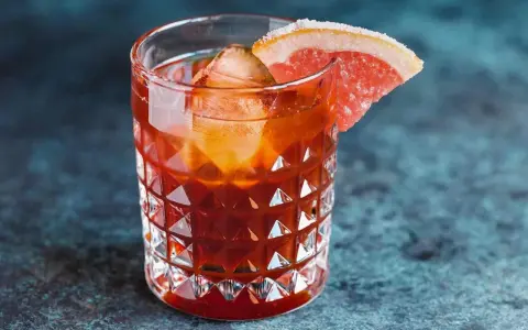 Jägermeister z colą w szklance z lodem i plasterkiem grejpfruta. Idealny na wieczorne orzeźwienie.