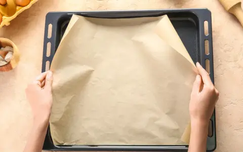 Ręce układają papier do pieczenia na blasze. To świetny sposób, by nic nie przywarło!