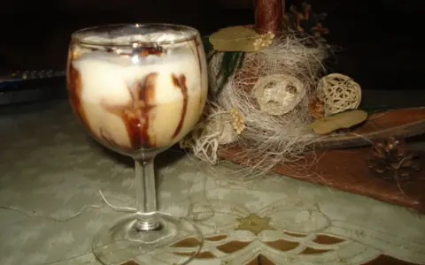 Pyszny drink z adwokatem, udekorowany czekoladą, na tle świątecznych ozdób.