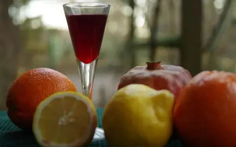 Szklanka z czerwonym napojem, obok pomarańcze, cytryna i granat. Czy to grenadyna? Hajduczek naturalnie.