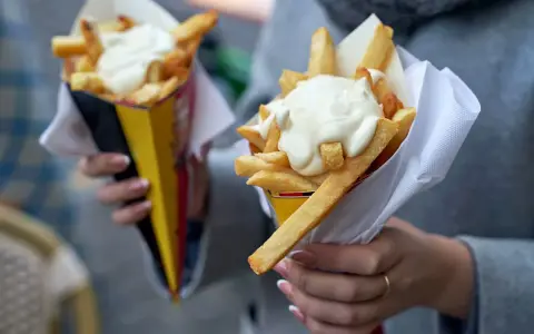 Dwie porcje chrupiących frytek w rożkach, polane obficie kremowymi sosami. Idealne na szybką przekąskę!
