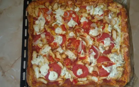 Pyszna, prostokątna pizza bez drożdży z kurczakiem, pomidorami, cebulą i serem.