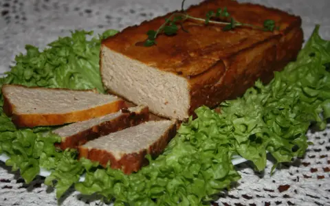 Pyszny pasztet drobiowy z wątróbką, pokrojony w plastry, podany na liściach sałaty. Idealny na kanapki.