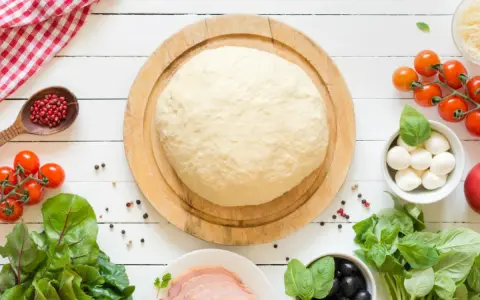 Świeże ciasto na pizzę, pomidorki, mozzarella, oliwki i szynka. Zastanawiasz się, ile może leżeć ciasto na pizzę w lodówce?