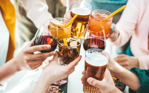 Ręce wznoszą kieliszki z winem, drinkami i piwem, celebrując wspólne chwile.