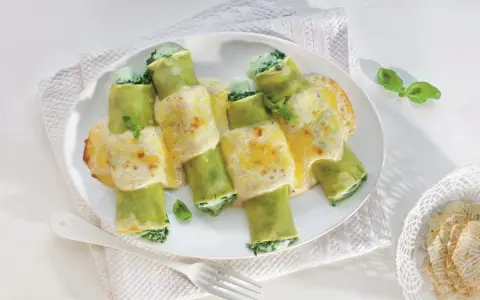 Zielone cannelloni ze szpinakiem, polane kremowym sosem i zapieczone z serem. Pyszne danie gotowe do podania.