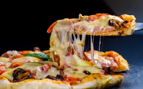 Rozciągający się ser z kawałka pysznej pizzy z kurczakiem, pomidorami i grzybami.