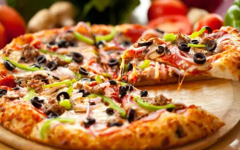 Gotowy spód do pizzy, z ciągnącym się serem, oliwkami, papryką i mięsem, aż chce się go włożyć do pieca!